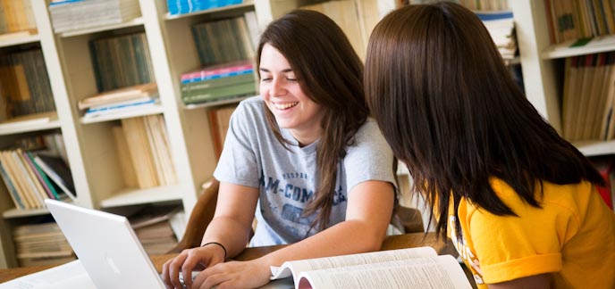 Female students working at laptop computer in library